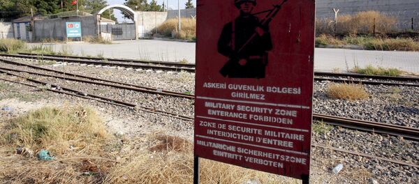 A Turkish military warning sign, with the closed Karkamis border gate in the background, is pictured in Karkamis, bordering with the Islamic State-held Syrian town of Jarablus, in Gaziantep province, Turkey - Sputnik Brasil