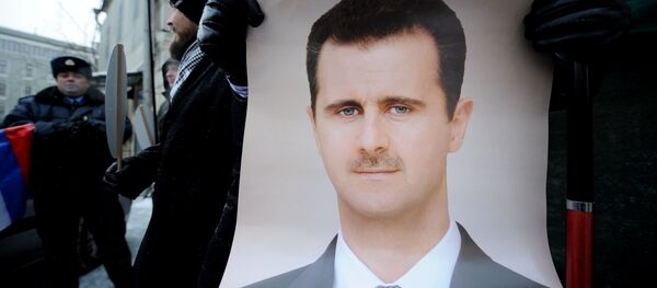 Demonstrante russo está empunhando o cartaz com a imagem do presidente sírio Bashar Assad durante uma ação de apoio proximo à embaixada síria em Moscou, 1 de fevereiro de 2012 - Sputnik Brasil