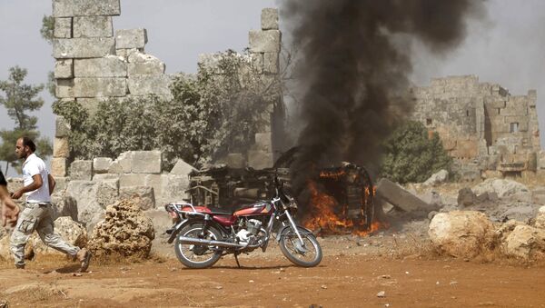A man runs past a burning military vehicle at a base controlled by rebel fighters from the Ahrar al-Sham Movement, that was targeted by what activists said were Russian airstrikes at Hass ancient cemeteries in the southern countryside of Idlib, Syria October 1, 2015. - Sputnik Brasil
