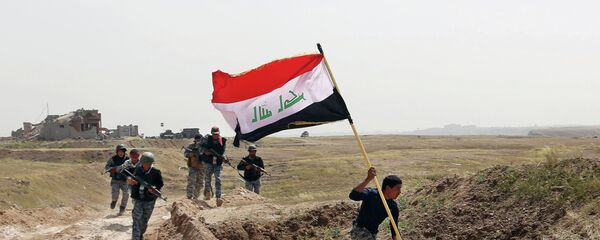Integrante das forças de segurança do Iraque corre com a bandeira do país após país cercar Tikrit, tomada pelo Estado Islâmico - Sputnik Brasil