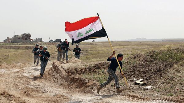 Integrante das forças de segurança do Iraque corre com a bandeira do país após país cercar Tikrit, tomada pelo Estado Islâmico - Sputnik Brasil