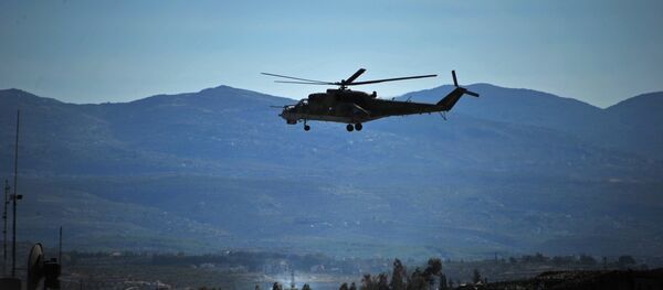 Um helicóptero Mi-24 russo patrulha a base aérea russa Hmeymim na Síria - Sputnik Brasil