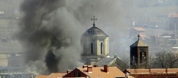 Uma coluna de fumaça sobre a Igreja Ortodoxa da Sérvia, que foi incendiada pelos extremistas da etnia albanesa em Kosovska Mitrovica, no norte de Kosovo, quinta-feira, 18 de março, 2004 - Sputnik Brasil