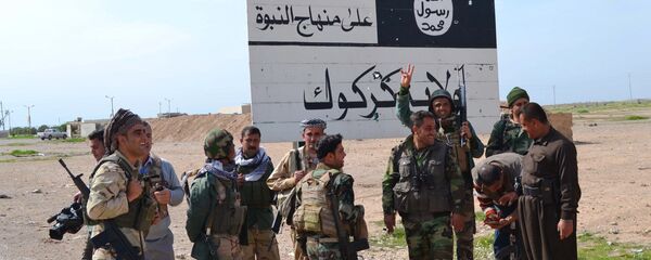 Iraqi Kurdish Peshmerga fighters stand next to an Islamic State (IS) group sign at the entrance to the northern Iraqi town of Hawija, south of Kirkuk on March 9, 2015 after they reportedly re-took the area from IS jihadists Iraqi Kurdish Peshmerga fighters stand next to an Islamic State (IS) group sign at the entrance to the northern Iraqi town of Hawija, south of Kirkuk on March 9, 2015 after they reportedly re-took the area from IS jihadists - Sputnik Brasil