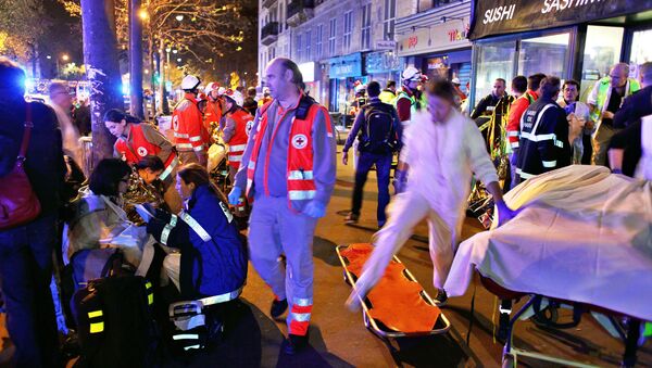 People rest on a bench after being evacuated from the Bataclan theater after a shooting in Paris, Saturday, Nov. 14, 2015 - Sputnik Brasil