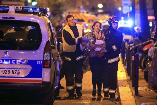 Bombeiros ajudam uma mulher ferida durante o tiroteio na sala de concertos Bataclan - Sputnik Brasil