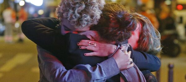 Três sobreviventes se dão um abraço fora da sala de concertos Bataclan, onde tinha acontecido um ataque com fuzil automático - Sputnik Brasil