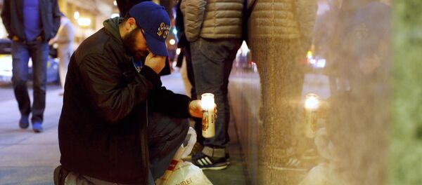 Um homem se persigna ao depositar flores em um memorial na entrada do Consulado-Geral da França em San Francisco em sinal de solidariedade com as vítimas do ataque em Paris - Sputnik Brasil