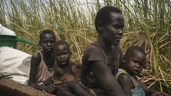 Uma mulher usa uma canoa para fugir com seus filhos de uma região pantanosa no Sudão do Sul. - Sputnik Brasil
