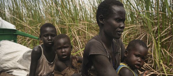 Uma mulher usa uma canoa para fugir com seus filhos de uma região pantanosa no Sudão do Sul. - Sputnik Brasil