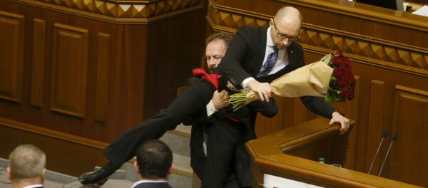 Oleg Barna, deputado da Rada, remove o primeiro-ministro Arseniy Yatsenyuk da tribuna, depois de lhe apresentar um buquê de rosas, durante a sessão do parlamento em Kiev, Ucrânia, 11 de dezembro de 2015 - Sputnik Brasil