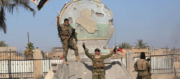 A member of the Iraqi security forces holds an Iraqi flag at a government complex in the city of Ramadi, December 28, 2015 - Sputnik Brasil