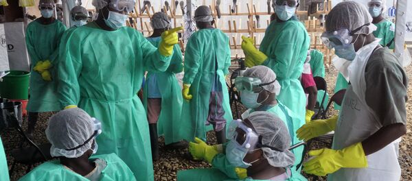 Health care workers inside a USAID-funded Ebola clinic with their Ebola virus protective gear in Liberia - Sputnik Brasil