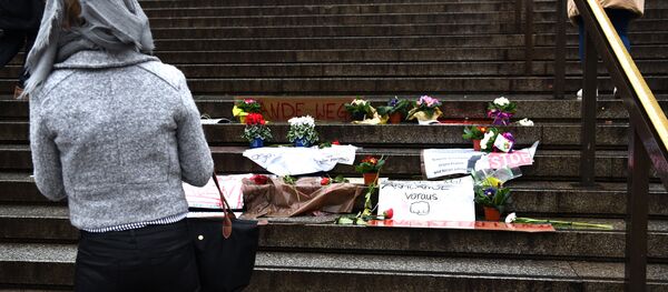 Mulher contempla as flores e cartas contra a violência e as ações de assédio sexual por imigrantes na véspera do Ano Novo, deixadas junto à catedral de Colônia, Alemanha, 11 de janeiro de 2016 - Sputnik Brasil