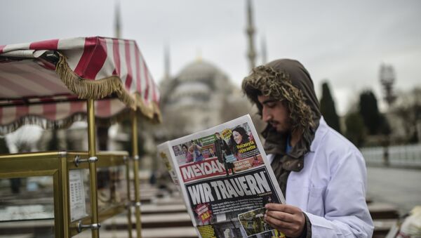 Homem empunha um jornal turco com o título em alemão Choramos perto de local do atentado em Istambul, Turquia, 13 de janeiro de 2016 - Sputnik Brasil
