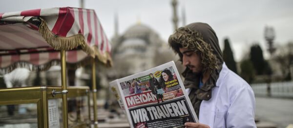 Homem empunha um jornal turco com o título em alemão Choramos perto de local do atentado em Istambul, Turquia, 13 de janeiro de 2016 - Sputnik Brasil