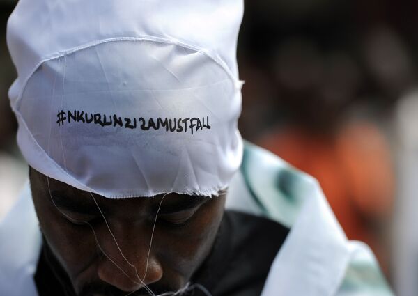 Um manifestante vestindo boné com uma inscrição dizendo Nkurunziza deve cair, em inglês e em forma de uma hashtag, em um ato de dezembro de 2015 Um manifestante vestindo boné com uma inscrição dizendo Nkurunziza deve cair, em inglês e em forma de uma hashtag, em um ato de dezembro de 2015 - Sputnik Brasil