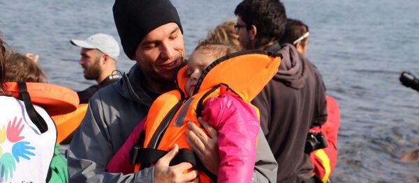 Edgard Raoul com criança refugiada desfalecida, na Ilha de Lesbos, na Grécia. - Sputnik Brasil