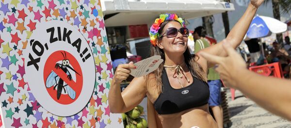 Viviane Oliveira, who's three months pregnant, dances next to a sign that reads in Portuguese : Get out Zika during a street carnival on Ipanema beach in Rio de Janeiro, Brazil, Sunday, Jan. 31, 2016 - Sputnik Brasil