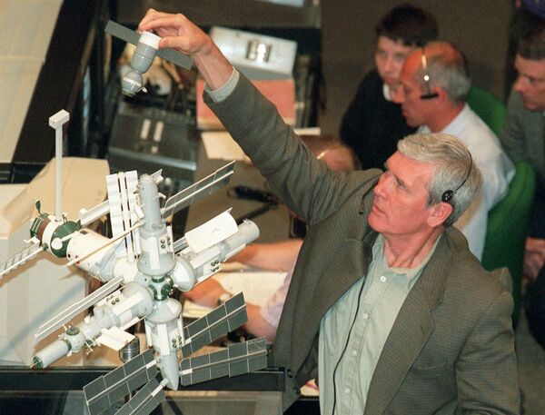 Yuri Blagov, vice-chefe de Controle da Missões, perto dum modelo da cápsula Soyuz e a estação MIR no Centro de Controle da Missão em Korolev, arredores de Moscou. Foto de arquivo de agosto 15, 1997 - Sputnik Brasil