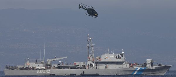 A small inflatable dinghy with a suspected smuggler on board is stopped by a Greek coastguard patrol boat, carrying migrants rescued at sea, as a helicopter from the European border control agency Frontex flies overhead, off Greece’s eastern Aegean Sea island of Lesbos on Thursday, Sept. 24, 2015 - Sputnik Brasil