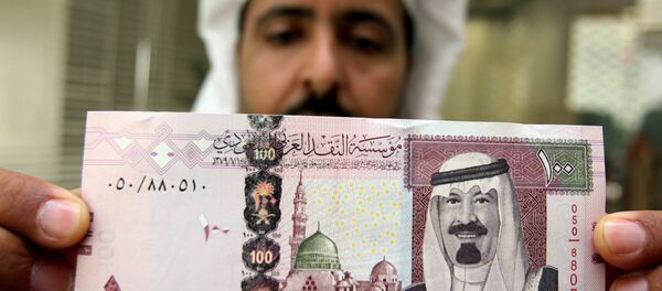 Bancário saudita mostra cédula com o retrato do rei Abdullah bin Abdul Aziz al-Saud em um banco de Riad - Sputnik Brasil