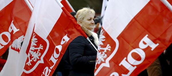 Mulher carrega bandeiras da Polônia durante protesto exigindo respeito à Constituição por parte do novo governo do país, Varsóvia, 12 de março de 2016 - Sputnik Brasil