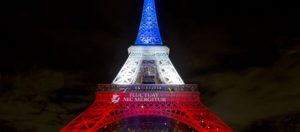 A photo taken on November 17, 2015 in Paris shows the Eiffel Tower illuminated with the colors of the French national flag in tribute to the victims of the November 13 Paris terror attacks. - Sputnik Brasil