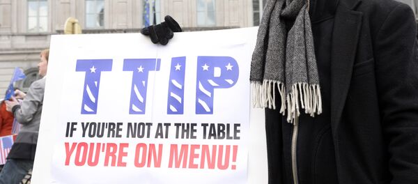 Um manifestante mostra o seu cartaz dizendo, em inglês: TTIP: se você não está à mesa, você está no cardápio durante um ato na entrada do Parlamento Europeu em 24 de fevereiro de 2016 - Sputnik Brasil