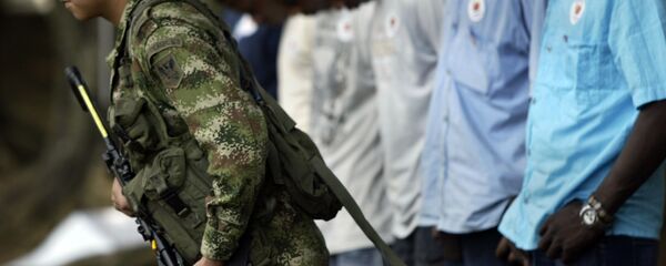 Um soldado do exército colombiano passa na frente de uma fila de guerrilheiros das FARC e do ELN Um soldado do exército colombiano passa na frente de uma fila de guerrilheiros das FARC e do ELN - Sputnik Brasil