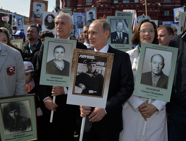 O presidente russo, Vladimir Putin com um retrato do seu pai, veterano de guerra durante a marcha Regimento Imortal na Praça Vermelha durante as celebrações do Dia da vitória em Moscovo, Rússia, 9 de maio de 2015 - Sputnik Brasil