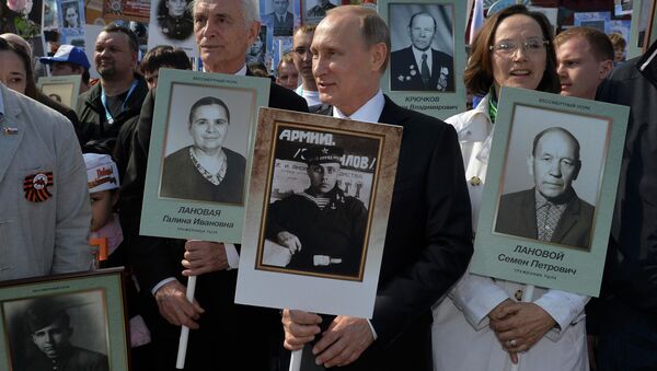 O presidente russo, Vladimir Putin com um retrato do seu pai, veterano de guerra durante a marcha Regimento Imortal na Praça Vermelha durante as celebrações do Dia da vitória em Moscovo, Rússia, 9 de maio de 2015 - Sputnik Brasil