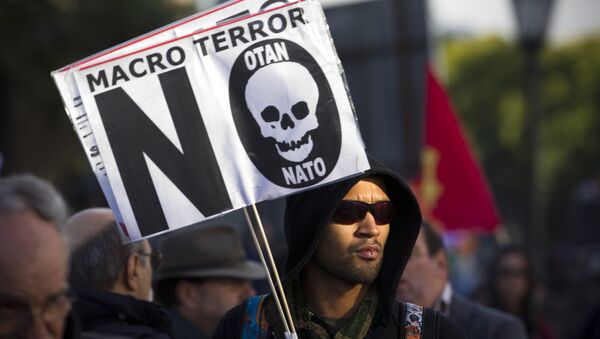 A protester holds a sign that reads Macro terror, no to NATO during a demonstration against NATO in Lisbon, on Saturday, Nov. 20, 2010 - Sputnik Brasil