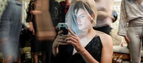 Modelo sentada com celular nos bastidores na Semana da Moda, na cidade de Almaty, Cazaquistão - Sputnik Brasil