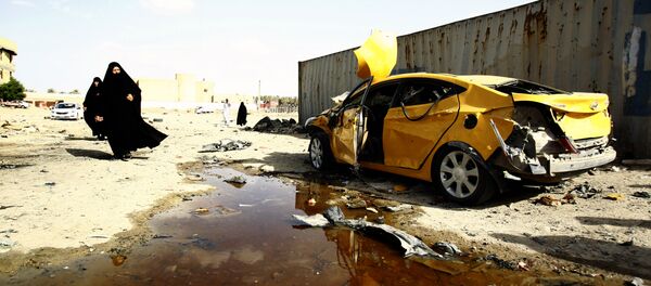 Iraqi women walk past a damaged car following a twin suicide bombing attack, claimed by the Islamic State (IS) group, in the southern Iraqi city of Samawah, situated deep in Iraq's Shiite heartland, on May 1, 2016 - Sputnik Brasil