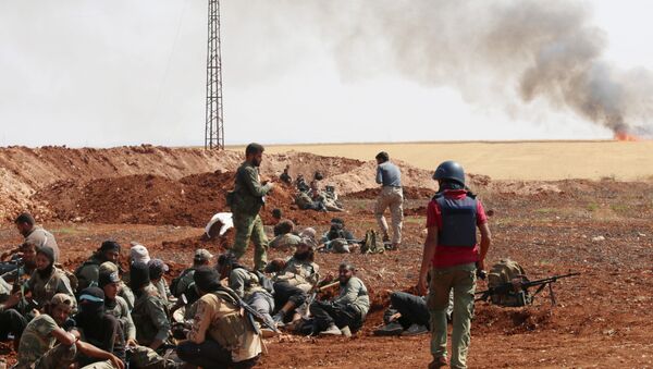 An unidentified photographer stands next to rebel fighters from Jaysh al-Islam (Army of Islam) holding a position behind a sand barrier on August 25, 2015, on the frontline in the Bashkoy area, on the northern outskirts of Aleppo, where opposition fighters are battling Syrian pro-government forces - Sputnik Brasil