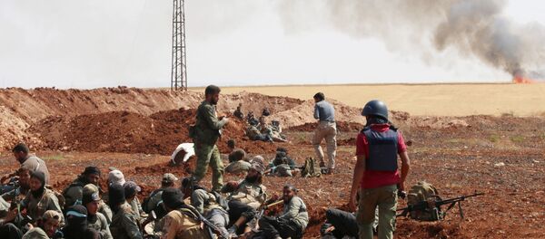 An unidentified photographer stands next to rebel fighters from Jaysh al-Islam (Army of Islam) holding a position behind a sand barrier on August 25, 2015, on the frontline in the Bashkoy area, on the northern outskirts of Aleppo, where opposition fighters are battling Syrian pro-government forces - Sputnik Brasil