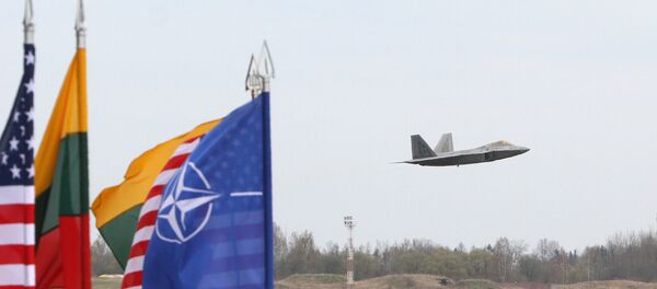 A US Air Force F-22 Raptor fighter aircraft flies at the Air Base of the Lithuanian Armed Forces in Šiauliai, Lithuania, on April 27, 2016 behind flags of US, Lithiania and the NATO A US Air Force F-22 Raptor fighter aircraft flies at the Air Base of the Lithuanian Armed Forces in Šiauliai, Lithuania, on April 27, 2016 behind flags of US, Lithiania and the NATO - Sputnik Brasil