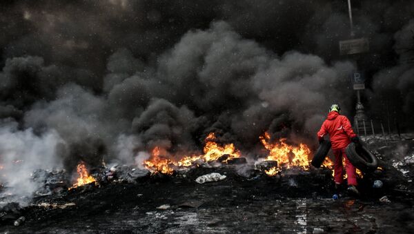 A protester adds tire to the fire in Maidan square in Kiev, Ukraine, Jan 22, 2014 - Sputnik Brasil
