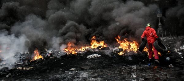 A protester adds tire to the fire in Maidan square in Kiev, Ukraine, Jan 22, 2014 - Sputnik Brasil