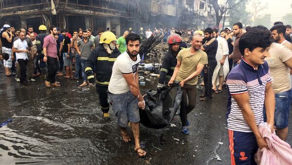 Bombeiros e civis iraquianos transportam corpos das vítimas mortos na explosão do carro-bomba na área comercial no bairro de Karada, Bagdá, no Iraque, domingo, 3 de julho, 2016 - Sputnik Brasil