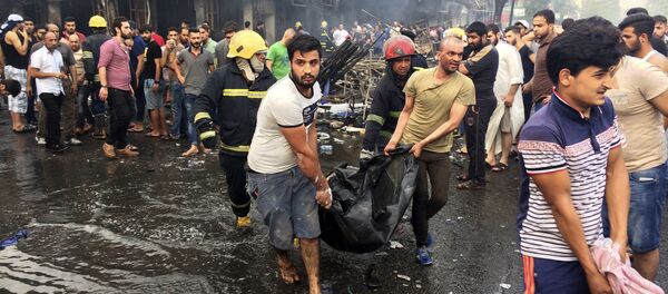 Bombeiros e civis iraquianos transportam corpos das vítimas mortos na explosão do carro-bomba na área comercial no bairro de Karada, Bagdá, no Iraque, domingo, 3 de julho, 2016 - Sputnik Brasil