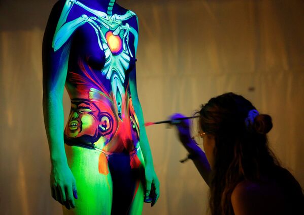 Um artista usa tinta para luz ultravioleta em uma modelo durante o Festival Mundial de Bodypainting em Portschach, no dia 1 de julho de 2016 - Sputnik Brasil