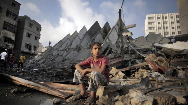 Menino palestiniano sentado sobre ruínas depois de bombardeio da Faixa de Gaza por Israel, agosto de 2014 - Sputnik Brasil