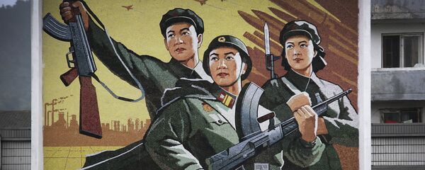 Um homem e uma mulher norte-coreanos caminham sob um mural com uma mensagem que diz: “Viva a grande vitória da política ‘Exército em primeiro lugar’!” no centro da cidade de Wonsan, na quarta-feira, 22 de junho de 2016, em Wonsan, Coreia do Norte. - Sputnik Brasil