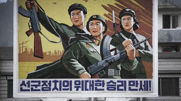 Um homem e uma mulher norte-coreanos caminham sob um mural com uma mensagem que diz: “Viva a grande vitória da política ‘Exército em primeiro lugar’!” no centro da cidade de Wonsan, na quarta-feira, 22 de junho de 2016, em Wonsan, Coreia do Norte. - Sputnik Brasil