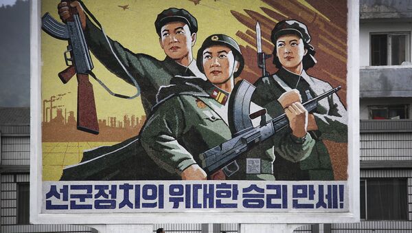 Um homem e uma mulher norte-coreanos caminham sob um mural com uma mensagem que diz: “Viva a grande vitória da política ‘Exército em primeiro lugar’!” no centro da cidade de Wonsan, na quarta-feira, 22 de junho de 2016, em Wonsan, Coreia do Norte. - Sputnik Brasil