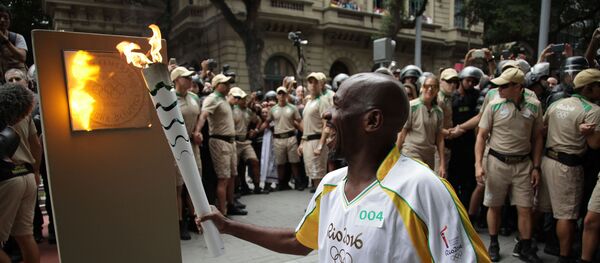 Cercado de seguranças, o carismático gari Renato Sorriso acende o primeiro dos cinco marcos olímpicos da cidade do Rio - Sputnik Brasil