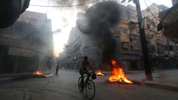 A man rides a bicycle past burning tyres, which activists said are used to create smoke cover from warplanes, in Aleppo, Syria August 1, 2016. - Sputnik Brasil