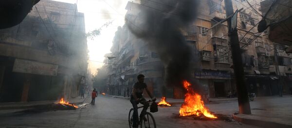 A man rides a bicycle past burning tyres, which activists said are used to create smoke cover from warplanes, in Aleppo, Syria August 1, 2016. - Sputnik Brasil